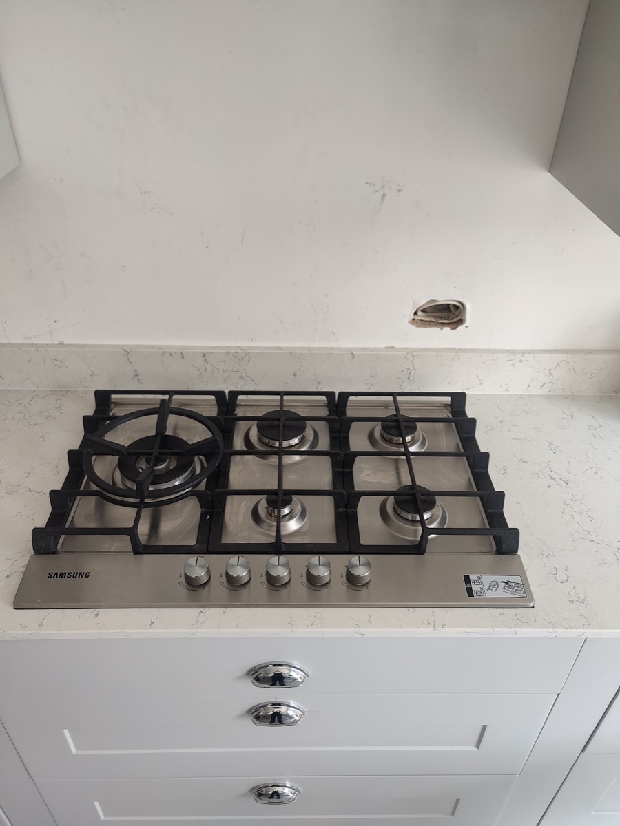 A five-burner Samsung stainless steel gas hob freshly fitted into a white kitchen worktop, ready for connection.